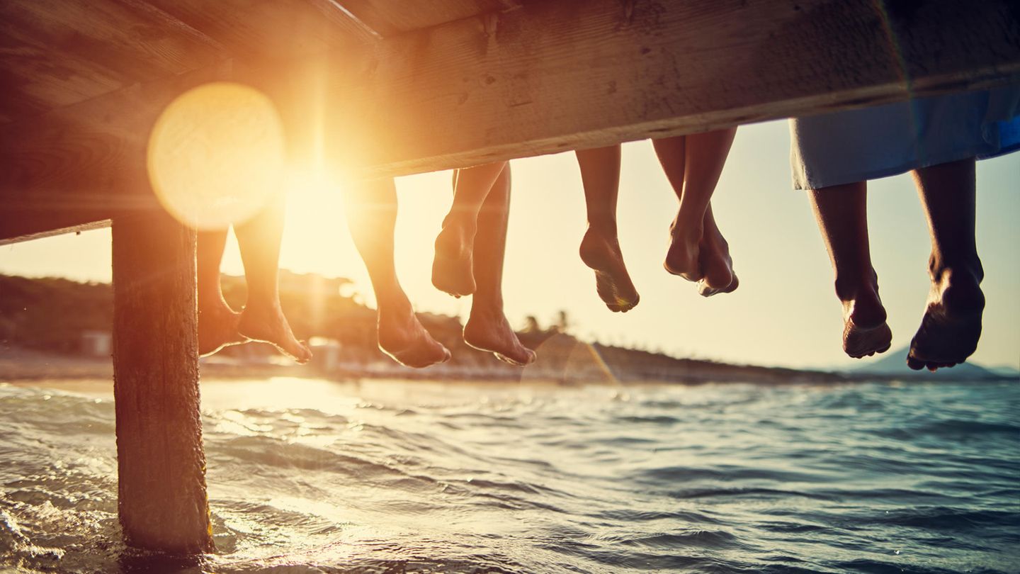 Menschen sitzen auf Steg am Wasser
