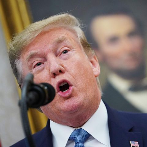 Donald Trump spricht in ein schwarzes Mikrofon. Unscharf im Hintergrund ist ein Ölgemälde von Abraham Lincoln zu sehen