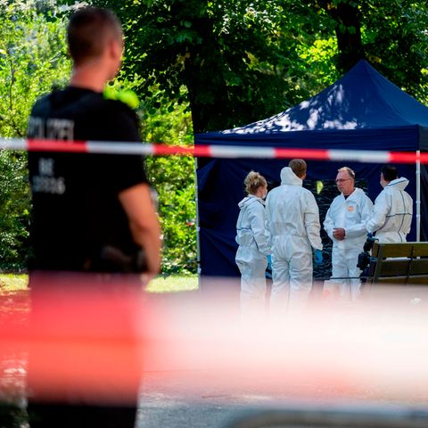 Ein Polizist sichert den abgesperrten Tatort, während vier Menschen in weißen Overalls offenbar Spuren sichern