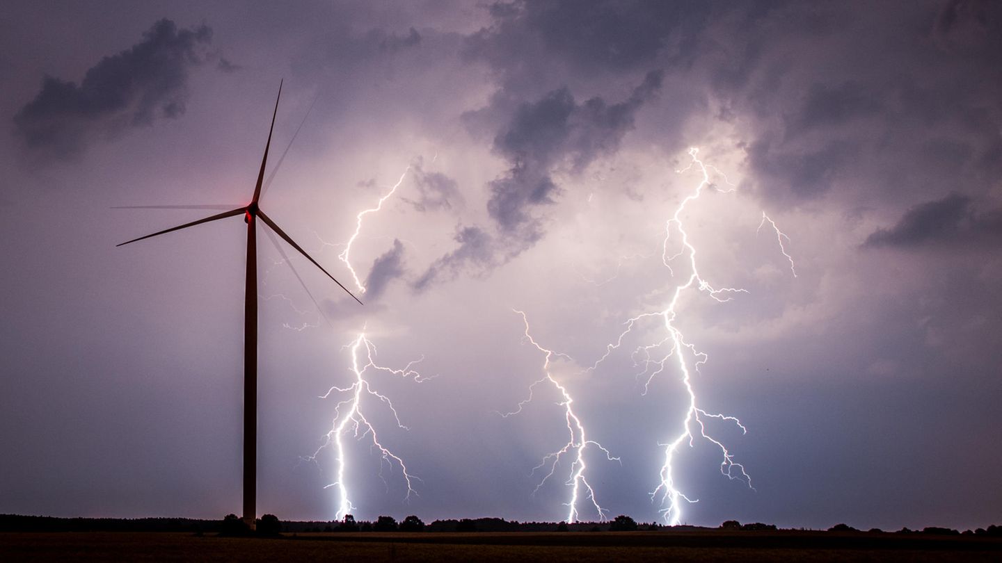 Unwetter am Nachthimmel über einem Feld mit einem Windrad.