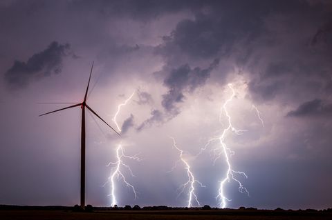 Unwetter am Nachthimmel über einem Feld mit einem Windrad.