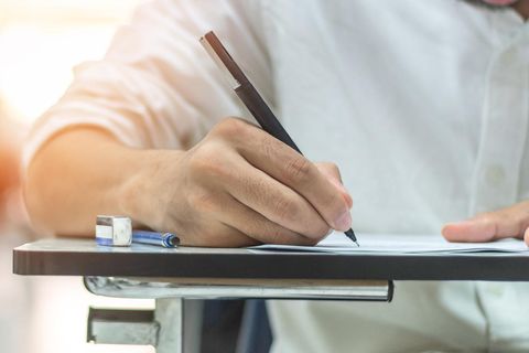 Eine Hand schreibt mit einem Stift auf ein Blatt Papier