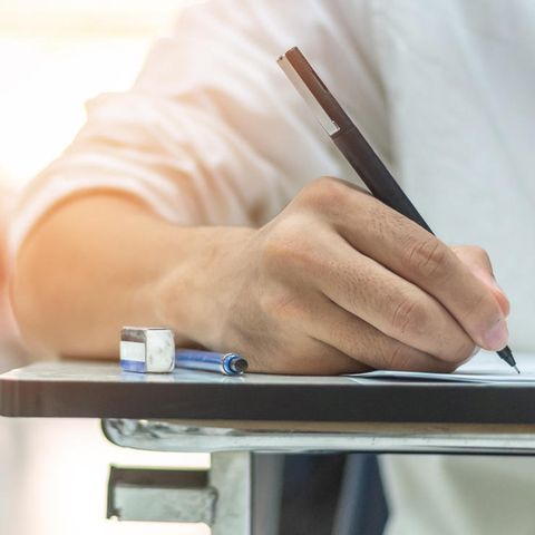 Eine Hand schreibt mit einem Stift auf ein Blatt Papier