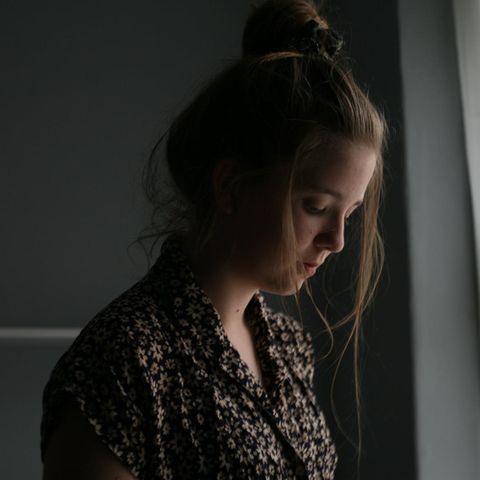 Woran erkennt man Depressionen? Frau steht traurig am Fenster