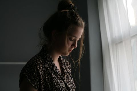Woran erkennt man Depressionen? Frau steht traurig am Fenster