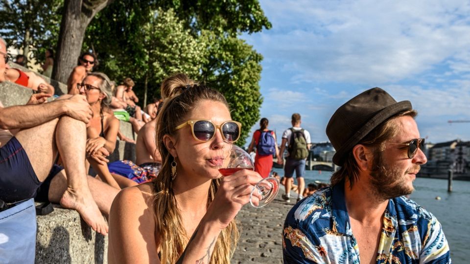 Städtreisen Schweiz: Am Ufer: Die Rheinstufen sind bevölkert von Sonnensuchern Am Ufer: Die Rheinstufen sind bevölkert von Sonnensuchern