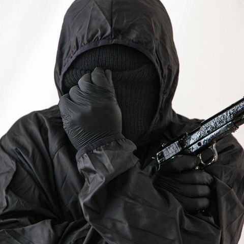 Vermummter Mann mit Handfeuerwaffe