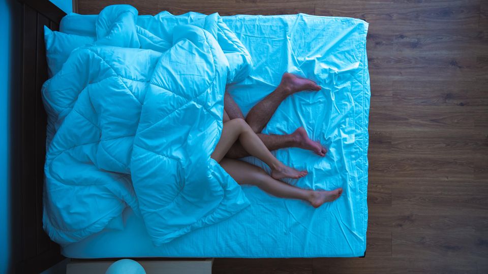 Zwei nackte Menschen liegen zusammen im Bett