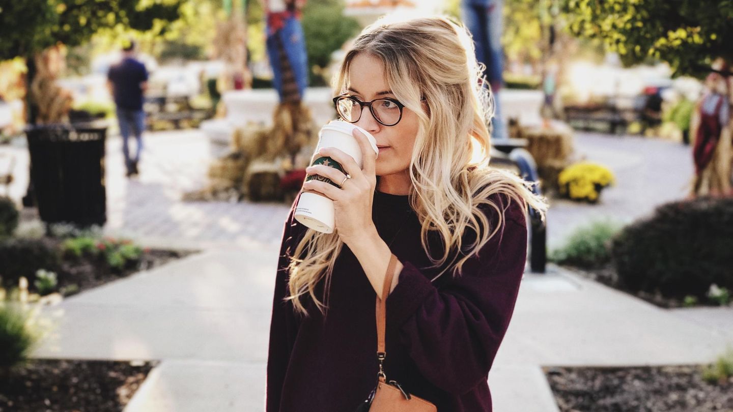 Ein Frau steht allein auf einem Weg und trinkt Kaffee