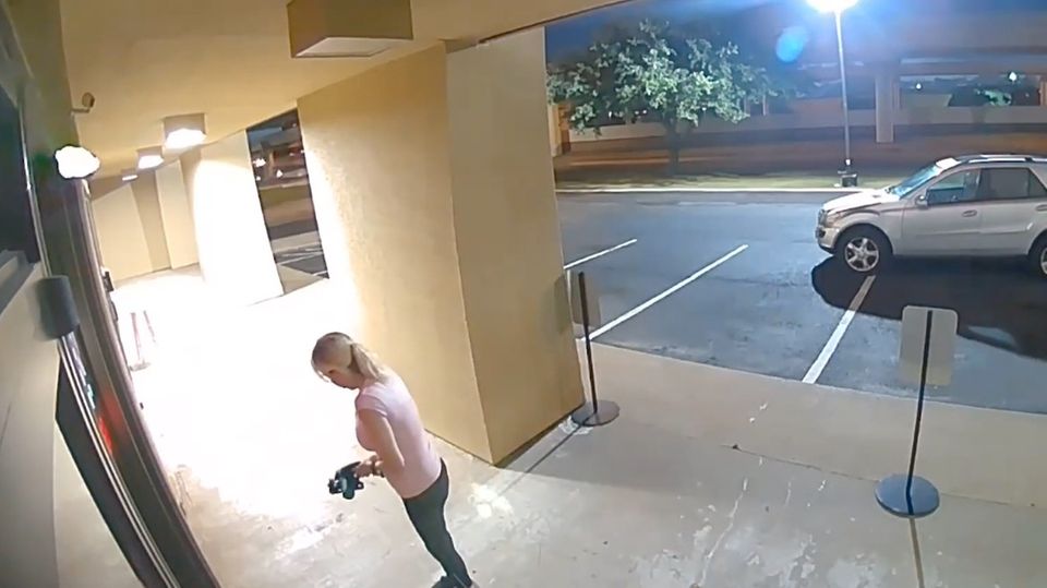 Frau steht mit einer Kreissäge in der Hand vor einem Gebäude