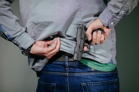Waffenschein: Mann steckt sich eine Schreckschuss-Pistole in den Hosenbund.