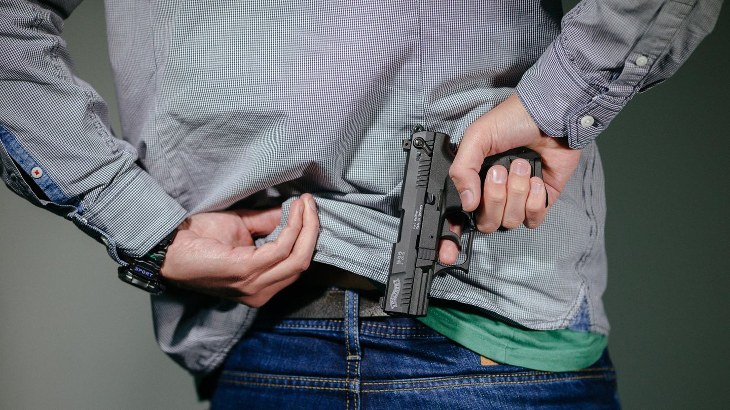 Waffenschein: Mann steckt sich eine Schreckschuss-Pistole in den Hosenbund.