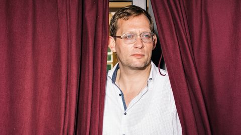 Erfolgsautor Clemens Meyer umrahmt von einem roten Vorhang