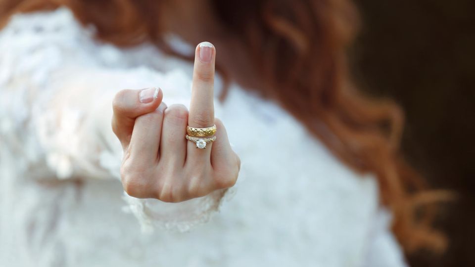 Eine Frau streckt den Ringfinger samt Verlobungs- und Ehering in die Höhe