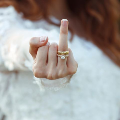 Eine Frau streckt den Ringfinger samt Verlobungs- und Ehering in die Höhe