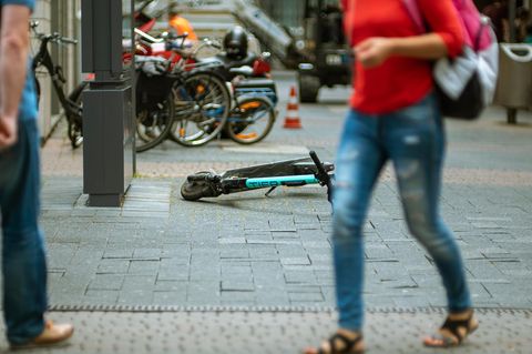 Ein E-Roller liegt mitten auf dem Gehweg