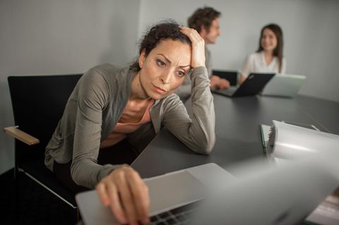 Eine gestresste Frau vor einem Laptop