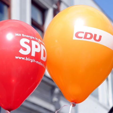 Ein SPD- und ein CDU- Luftballon schweben in der Innenstadt