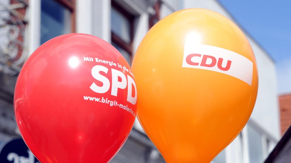 Ein SPD- und ein CDU- Luftballon schweben in der Innenstadt
