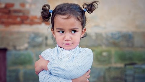 Ein kleines Mädchen guckt wütend mit verschränkten Armen