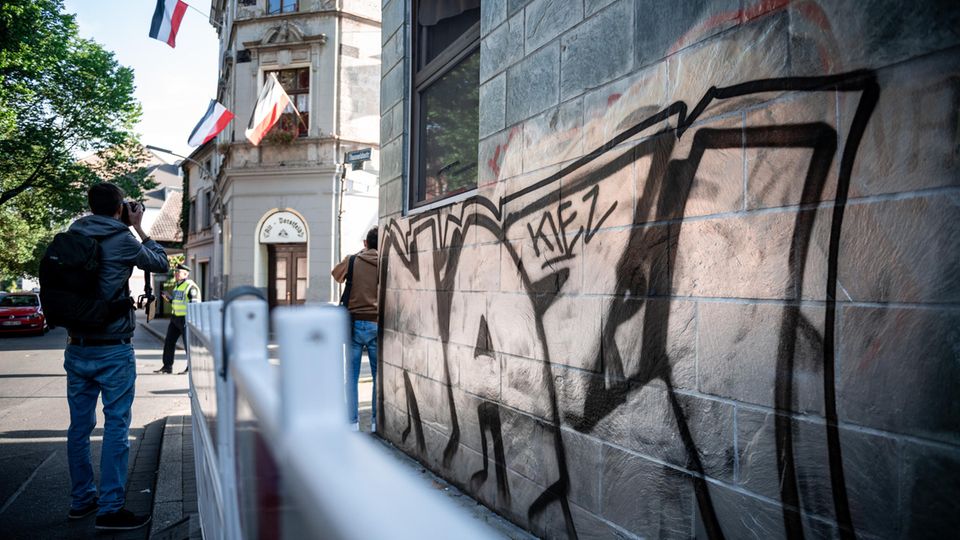 "Nazi-Kiez" steht an einer Wand, gegenüber eines Hauses, an dem Reichsflaggen aus den Fenstern hängen