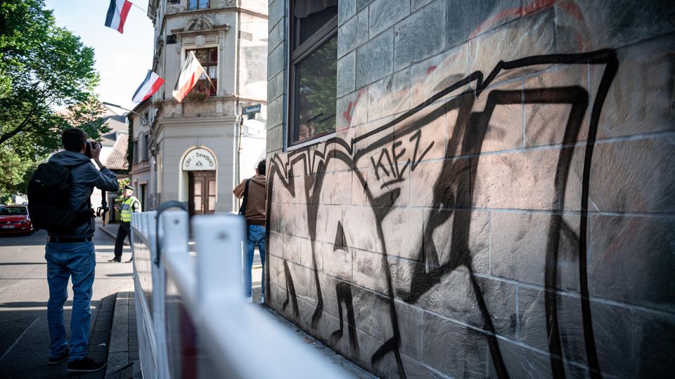 "Nazi-Kiez" steht an einer Wand, gegenüber eines Hauses, an dem Reichsflaggen aus den Fenstern hängen "Nazi-Kiez" steht an einer Wand, gegenüber eines Hauses, an dem Reichsflaggen aus den Fenstern hängen