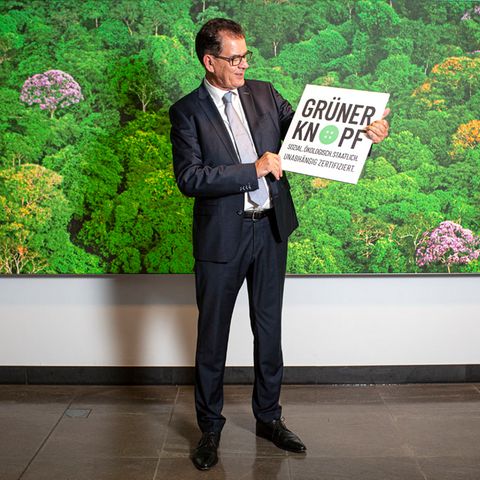 Entwicklungsminister Gerd Müller hält ein Schild mit der Aufschrift "Grüner Knopf"