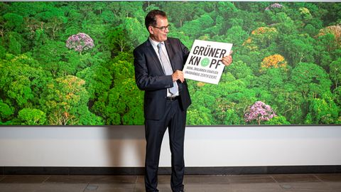 Entwicklungsminister Gerd Müller hält ein Schild mit der Aufschrift "Grüner Knopf"
