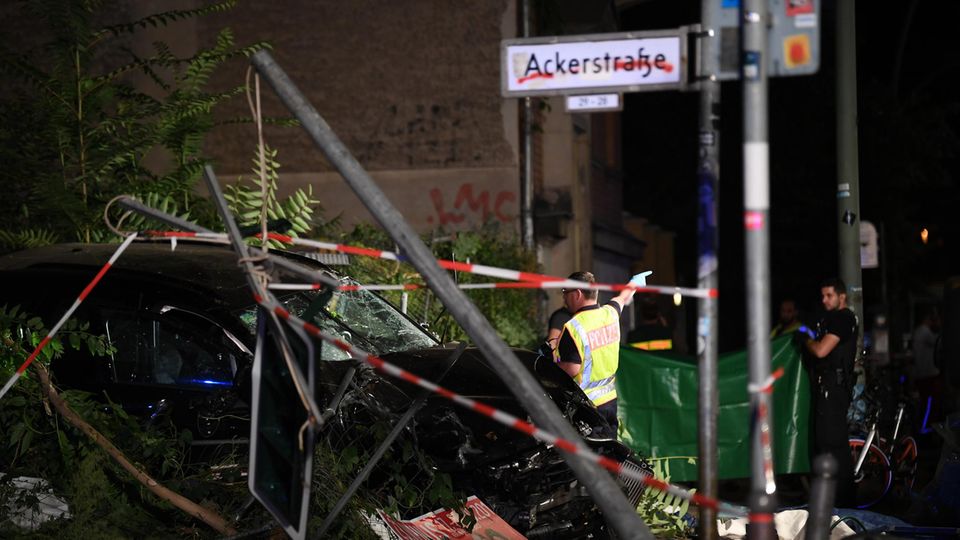 Nachrichten aus Deutschland: Vier Tote nach Verkehrsunfall in Berlin An einem zerstörten Auto halten Polizisten ein Plane