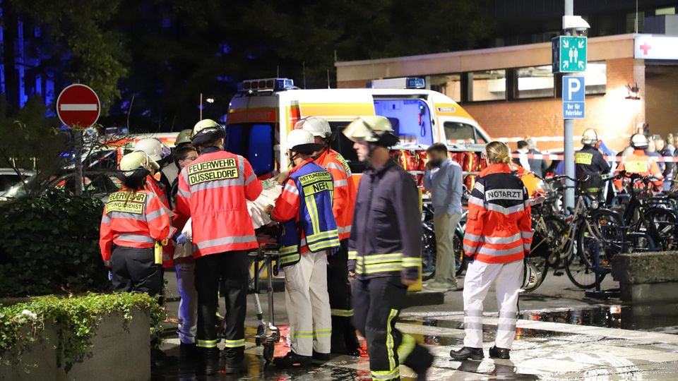 Feuerwehrleute und eine Notärztin stehen nach einem Brand im Marien Hospital um einen Patienten auf einer Liege herum.