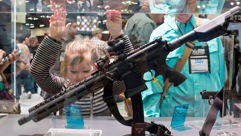 Ein junges Mädchen bestaunt auf dem jährlichen Treffen der NRA ein Gewehr.