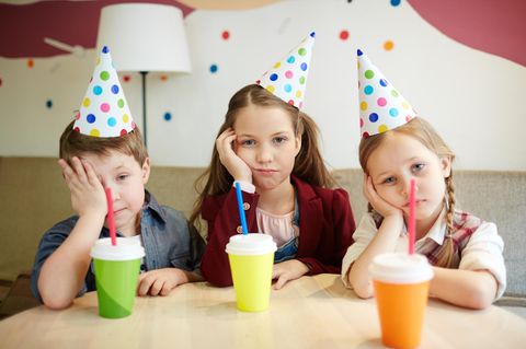 Drei Kinder mit Partyhütchen gucken genervt