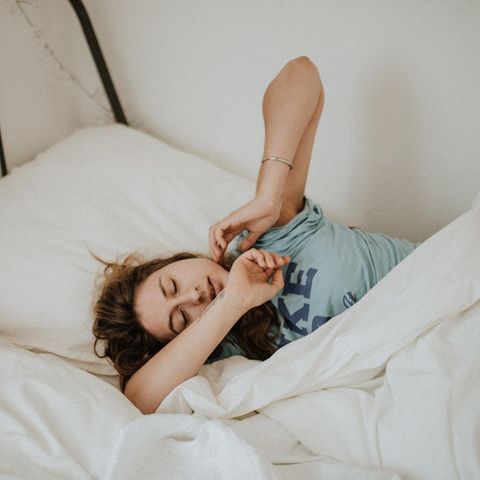 Frau liegt im Bett und räkelt sich.