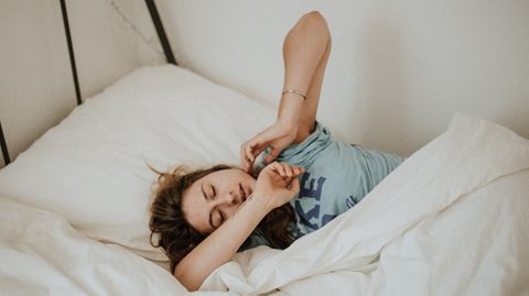 Frau liegt im Bett und räkelt sich.