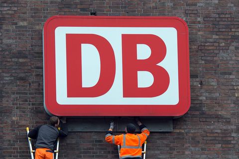 Monteure arbeiten an einem Unternehmensschild der Deutschen Bahn