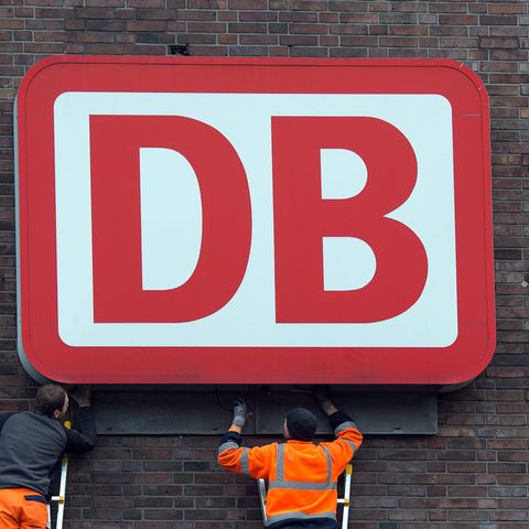 Monteure arbeiten an einem Unternehmensschild der Deutschen Bahn