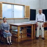 Eine Japanerin sitzt im Schaukelstuhl, ein Japaner steht in zwei Metern Entfernung