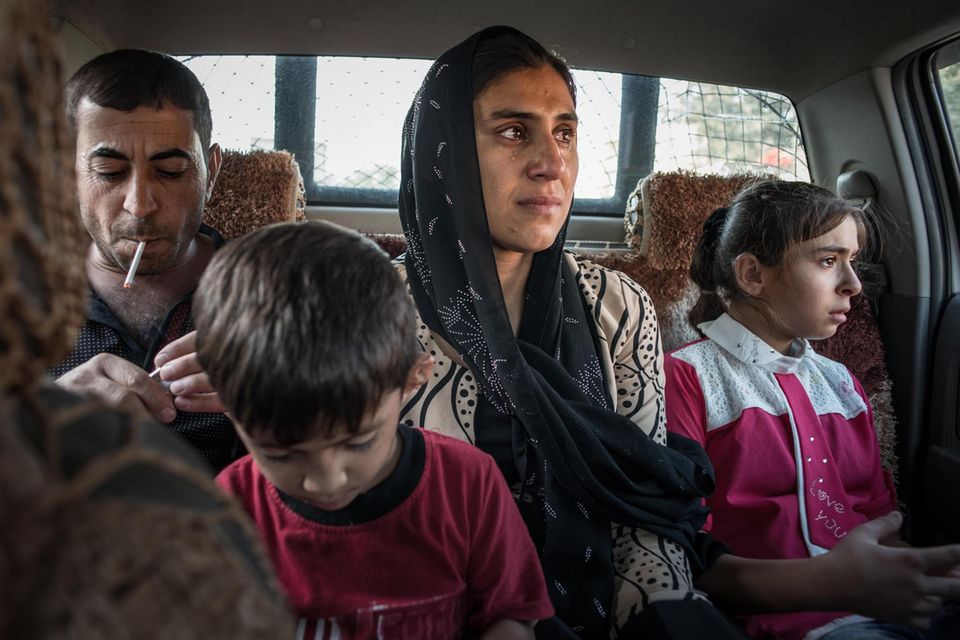 Vater Hazim (links) begleitet seine Frau Jaleela (Mitte) und die Kinder Khairi (Vordergrund) und Marya (rechts) zum Flughafen Erbil. Sie wissen nicht wann sie sich wiedersehen werden. Mutter Jaleelazusammen mit ihren Kindern Khairi und Marya auf dem Weg nach Arbil. Ihr Mann Hazm begleitet sie zum Flughafen