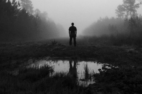 Umriss eines Mannes, der in einem Moor steht. Es ist nebelig