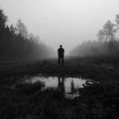 Umriss eines Mannes, der in einem Moor steht. Es ist nebelig