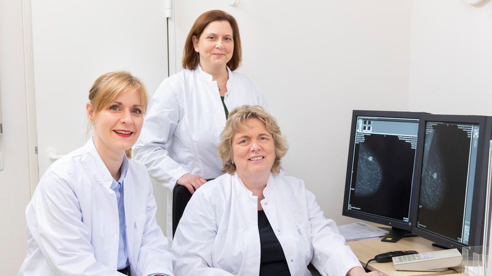 Prof. Dr. Nadia Harbeck (m.), Dr. Friederike Hagemann (l.) und Dr. med Rachel Würstlein (r.) an einem Schreibtisch sitzend
