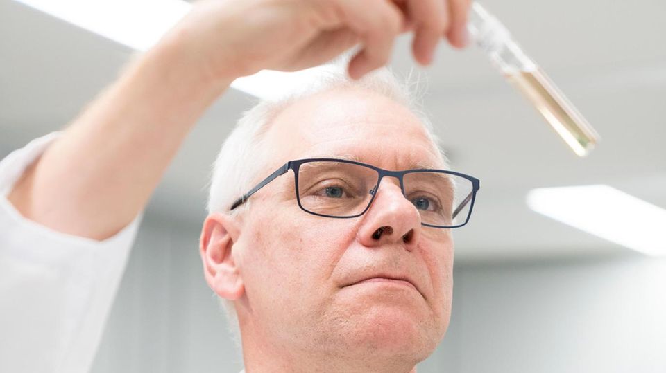 Dr. Wolfgang Treder hält ein Reagenzglas in der Hand