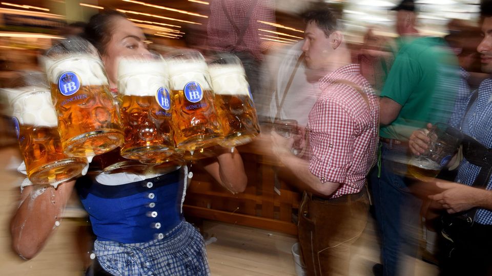 Eine Bedienung trägt volle Maßkrüge mit Bier auf dem Oktoberfest