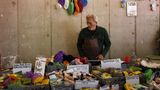 Auf einem Tisch vietet ein alter Mann waren an, die in der DDR produziert worden sind