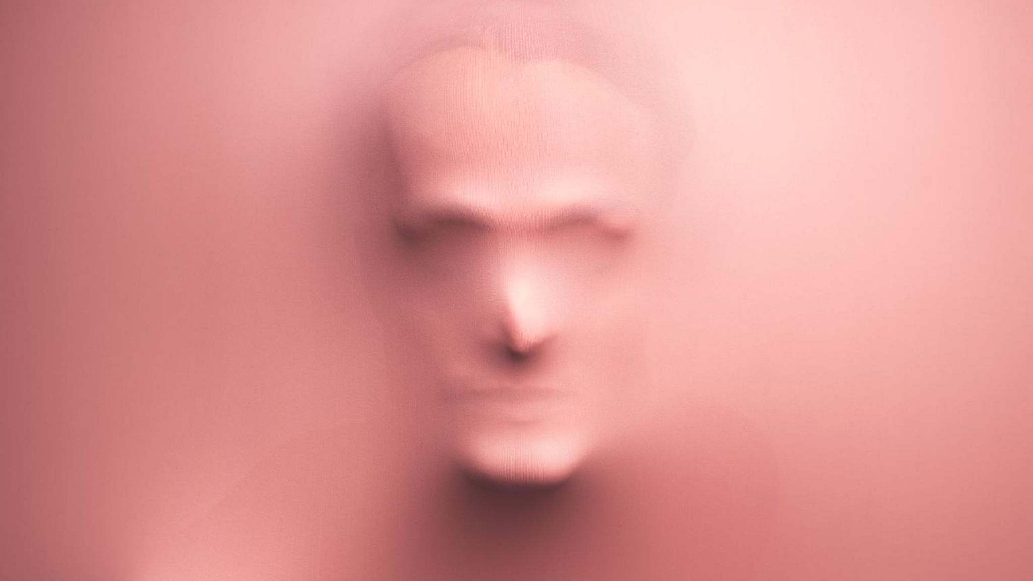 Gesicht eines Mannes, das sich durch rosa Lycrastoff abzeichnet