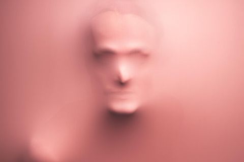 Gesicht eines Mannes, das sich durch rosa Lycrastoff abzeichnet
