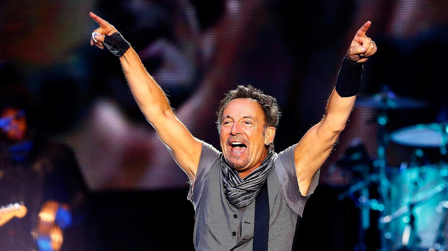 Bruce Springsteen jubelt mit umgehangener Gitarre auf einem Konzert