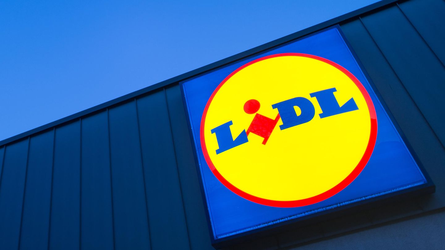 Das Logo eines Lidl-Supermarktes in Berlin-Reinickendorf leuchtet vor dem Abendhimmel.