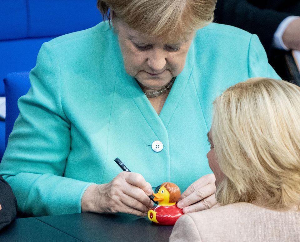Bundeskanzlerin Angela Merkel unterschreibt eine Quietscheente
