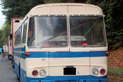 Ein weißer Passat steht im Innenraum eines weiß-blauen Reisebusses aus den 70er Jahren.
